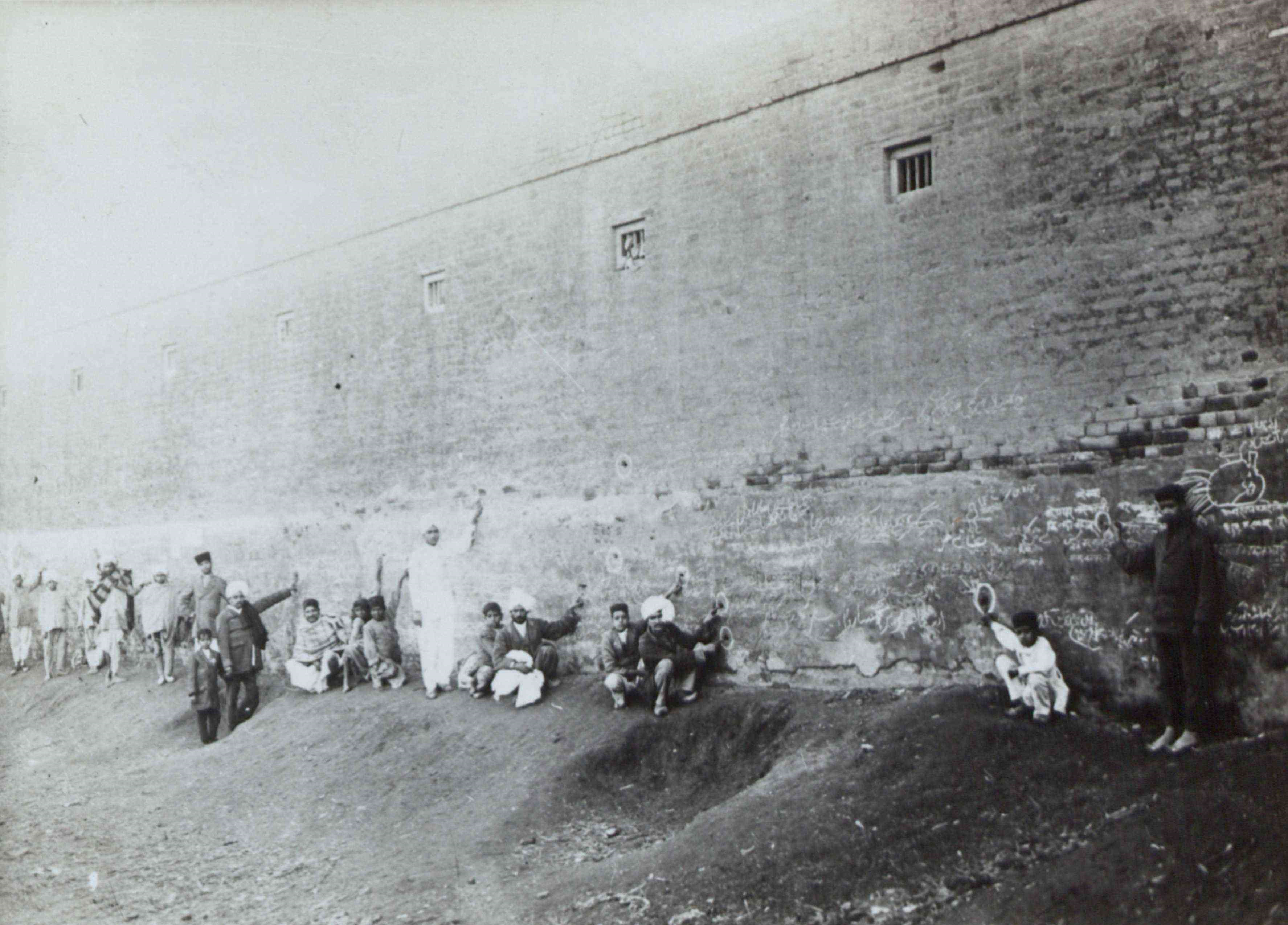 Yüksek duvarlarla çevrili Jallianwala Bagh'daki kurşun izlerini işaret eden insanlar, 1919.